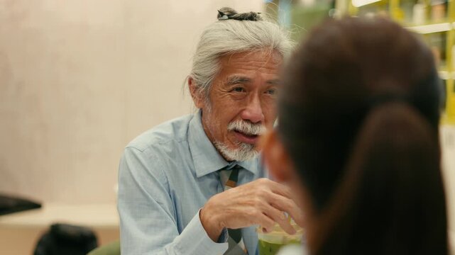 Close up of expressive senior businessman talking in cafe at night