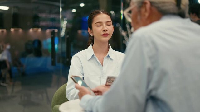 Smiling assistant with two phones talks to boss over cafe table