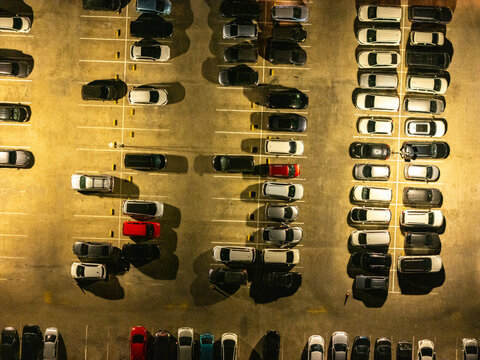 Aerial view of a parking lot at night with rows of parked cars illuminated by artificial lights in Semarang, Central Java, Indonesia.