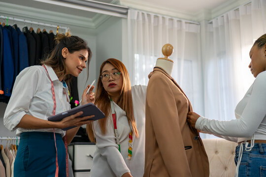 Women discussing blazer fit with tablet and pen at tailor shop