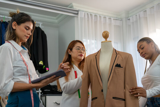 Women checking blazer fit on mannequin in tailoring studio