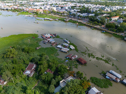 Aerial view of floating houses on the Hau River with lush vegetation and the town of Chau Doc in the background, Chau Doc, An Giang, Vietnam.