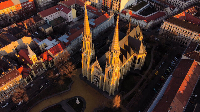 Aerial view of St. Elizabeth of Hungary Parish Church surrounded by historic urban rooftops and streets in the golden hour light in Budapest, Hungary.