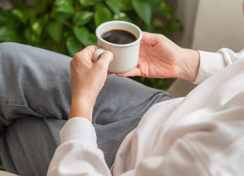 Person holding a cup of coffee during a quiet morning routine, embracing a digital detox and mindful relaxation while enjoying natural light and a slower pace of life