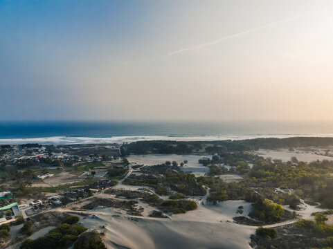 Aerial view of the expansive sand dunes and coastal vegetation along the shoreline with the Indian Ocean in the background in Kecamatan Kretek, Daerah Istimewa Yogya, Indonesia.