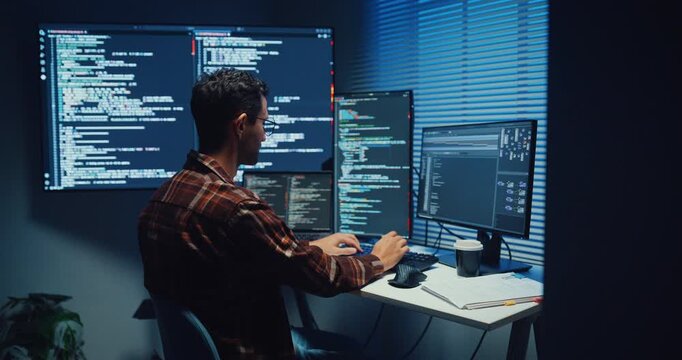 Young Caucasian male programmer write code on computer in home office at late night. AI technology, cybersecurity, software developer, freelance innovation, database system, digital network concept.