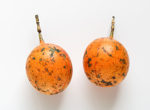 Two whole sweet granadilla passion fruit, isolated on a white background.