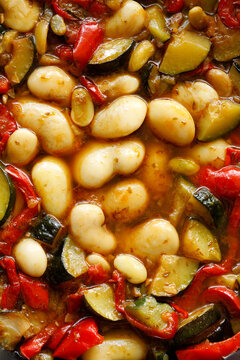 Stewed butter beans with zucchini and red peppers, vegetarian stew top view full frame