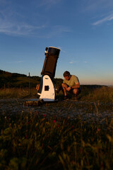 Amateur astronomer preparing telescope during sunset for night observations of stars, Milky Way, Moon and Planets. © astrosystem