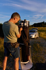 Amateur astronomer preparing and collimating telescope during sunset for night observations of stars, Milky Way, Moon and Planets. © astrosystem