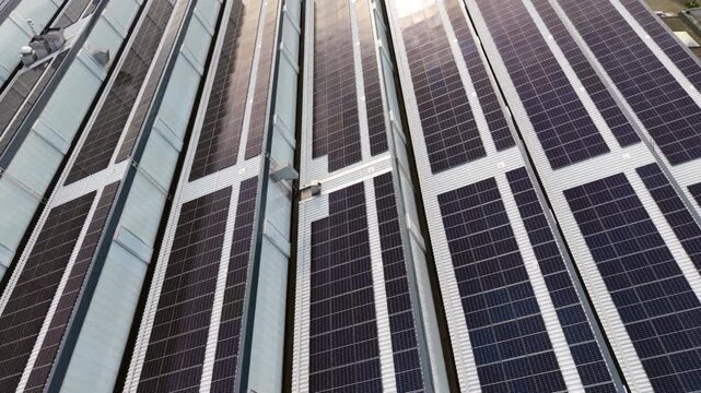 4k Aerial view solar panel facade on modern high rise with bright sun flare, glass and metal surfaces, strong geometric lines, clean energy architecture