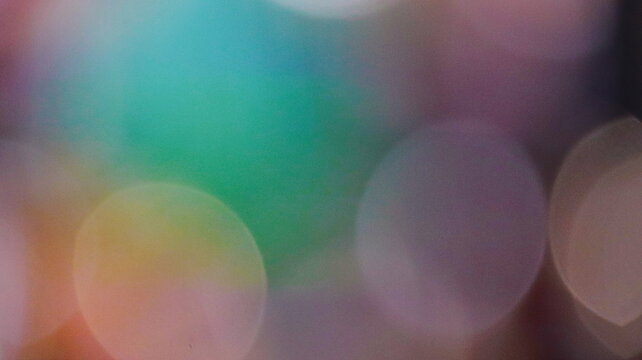Abstract colorful bokeh light background with soft blurred circles of teal green and purple hues for creative design texture