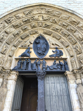 Gothic cathedral portal with carved stone archivolts, tympanum sculptures and old wooden doors