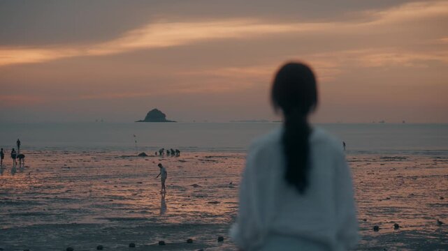 Rear View of Woman Looking at People on Mudflat during Golden Hour Sunset