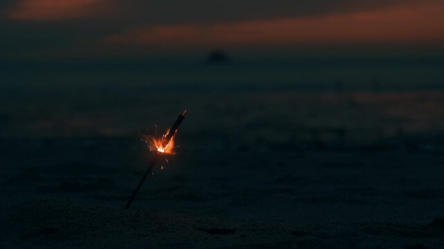 Sparkler Burning and Sparkling on Sandy Beach during Dusk at Coast
