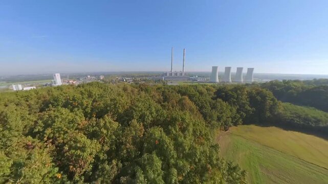 FPV drone climbs above forest treetops to reveal redundant industrial cooling towers of the Detmarovice Coal Power Plant, suitable for documenting coal power, industrial decline and energy transition