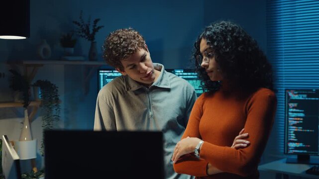 Diverse team software developer discuss AI coding project strategy in dark office at night. Creative startup group brainstorming, Mentor code review training, Digital communication innovation concept.