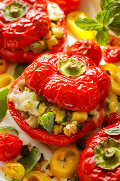 Baked stuffed red bell peppers  with oat groats with zucchini, mushrooms and melted cheese, roasted cherry tomatoes and basil, vertical