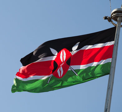 National Flag of Kenya Waving on Flagpole Against Blue Sky