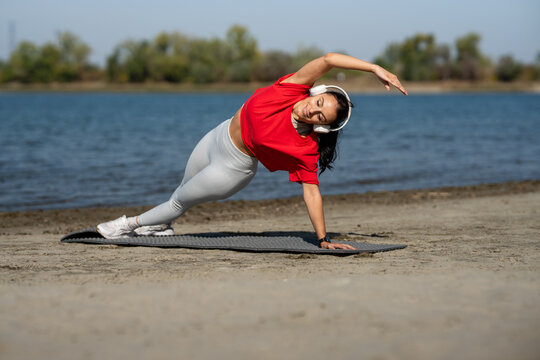 Woman practicing yoga side plank on beach