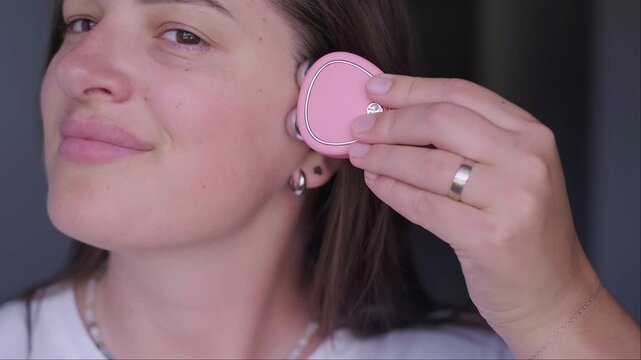 Woman using pink microcurrent facial device for skin lifting and massage Self care beauty routine and anti aging treatment for youthful glowing skin and modern wellness technology at home