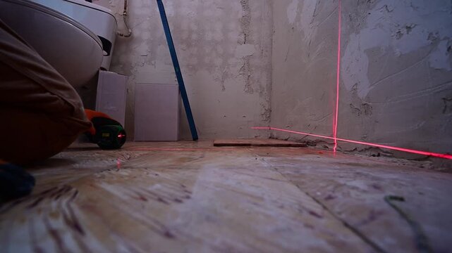 Construction worker using laser level for floor tiling
