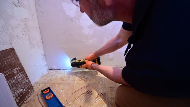 Man sanding a plaster wall with an oscillating multi-tool during renovation