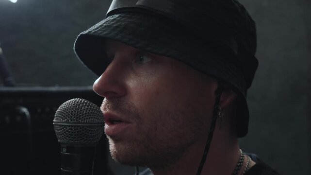 Rap singer performing into microphone, expressive portrait of vocalist singing lyrics while practicing contemporary music and vocal delivery.