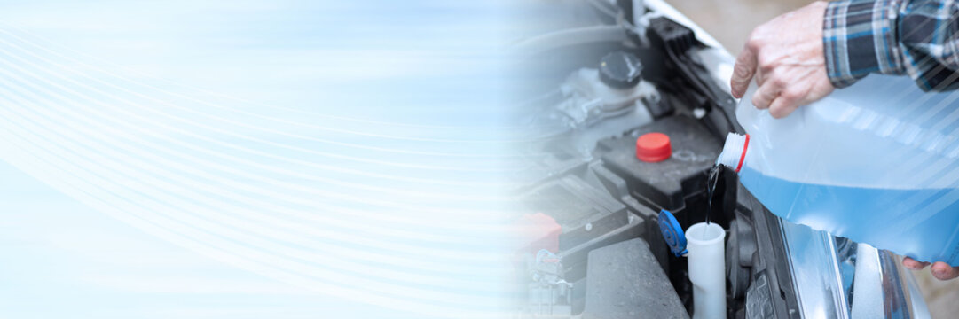 Hands of mechanic pouring windshield washer fluid in a car; panoramic banner