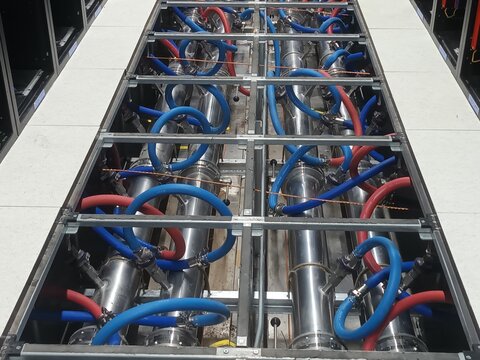 Liquid cooling system piping infrastructure under raised floor in high performance data center, blue and red coolant pipes for server racks.