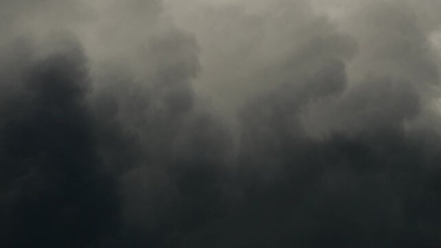 Dark gloomy storm clouds rolling across the overcast sky before heavy rain, dramatic moody gray cloudscape with billowing dense clouds, stormy weather background, monsoon season atmosphere