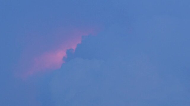 Blue cumulus cloud against a vivid pink and purple sunset sky, dreamy surreal pastel gradient cloudscape with soft glowing light