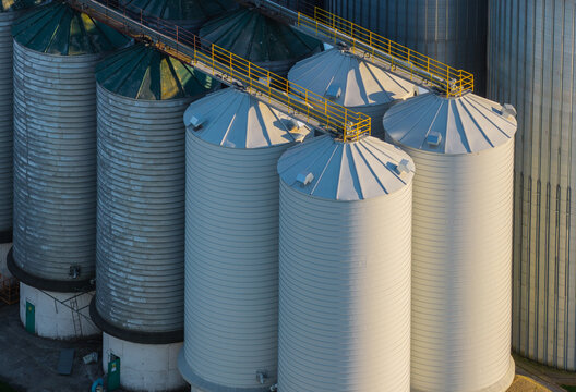 Aerial view of industrial grain silos with metal surfaces and yellow catwalks in Kwidzyn, Pomeranian Voivodeshi, Poland.