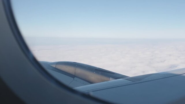 Airplane Wing and Engine Above Cloud Layer Viewed Through Window, Calm Flight Travel Journey Across Expansive Blue Sky, Aviation Aerial Cloudscape Scene