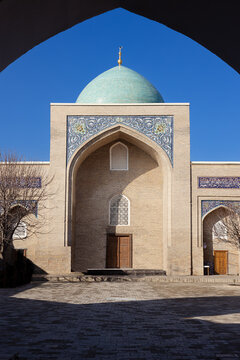 Barak Khan Madrasah in Tashkent framed through a pointed archway with turquoise dome and tilework facade. Ideal for travel publications, cultural heritage materials, and architectural design refere...