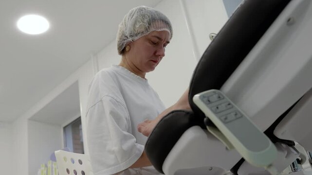 Pedicurist works on clients foot during pedicure, carefully tending toes beside padded salon chair. Focused woman provides personal foot care in clean treatment room, attending to toenails with hands.
