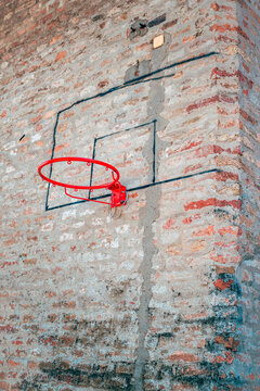 Improvised basketball hoop attached to a historic brick fortress wall. Concept of streetball culture, urban sports, makeshift playgrounds, local community recreation, and gritty sports aesthetics.