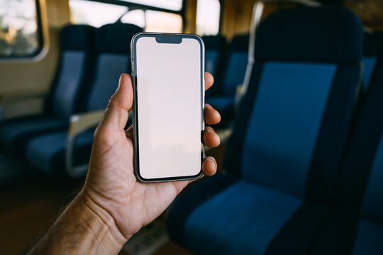 Modern smartphone with a clean empty screen inside a passenger railway carriage, surrounded by softly blurred seats and windows. Travel, technology, communication and mobile advertising theme.