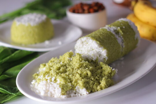 Crumbled spinach puttu with grated coconut and kadala curry served with cylindrical puttu