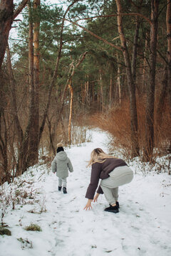 Mother and child walking a snowy winter forest path