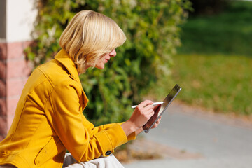 Woman Using Tablet with Stylus Outdoors, Digital Creativity and Remote Work © Yurii_gold
