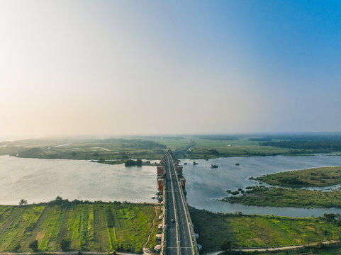Aerial view of Kabanaran Bridge spanning the Progo River, surrounded by lush green agricultural fields and wetlands in Kecamatan Srandakan, Daerah Istimewa Yogya, Indonesia.