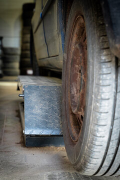 Worn Car Tire and Rusty Steel Wheel Rim at an Automotive Workshop