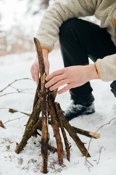 Person building campfire structure in winter forest