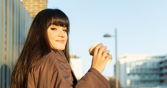 Young woman enjoying coffee in urban morning sunshine