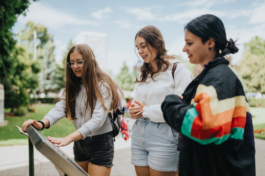 Three teenage friends read a park information board while standing together. They chat and point at the sign during a relaxed outdoor outing.