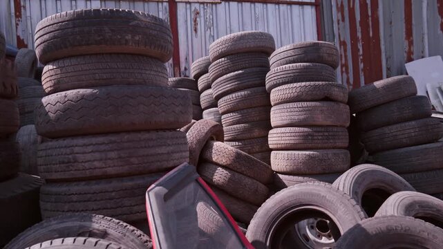 Large Pile of Stacked Old Used Car Tires in Auto Scrapyard