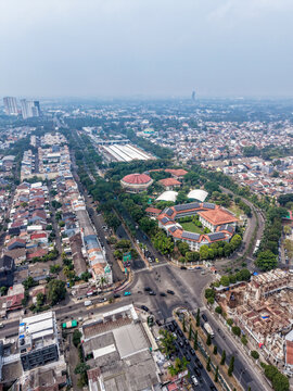 Aerial view of the urban landscape in BSD City featuring a circular building, a U-shaped complex with solar panels, and busy roads in Kecamatan Serpong, Banten, Indonesia.