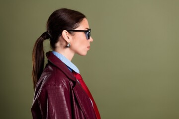 Profile portrait of a stylish business woman in sunglasses and maroon leather jacket with red tie and ponytail © deagreez