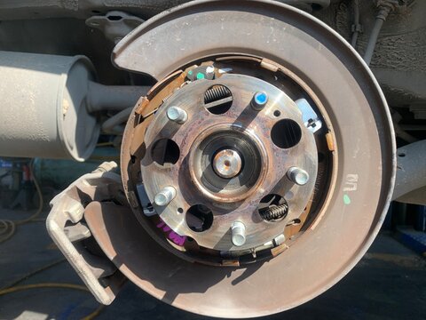Car Brake System Close-up: A detailed view of a car's rear brake assembly, showing the rotor, caliper, and brake shoes, highlighting mechanical components and maintenance.